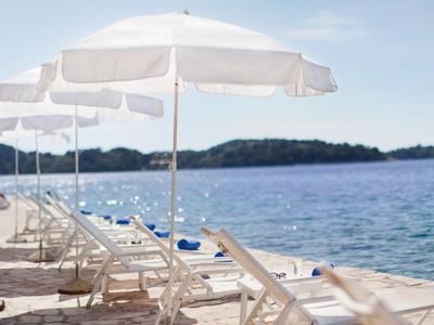 Plaża z białymi leżakami i parasolami przy spokojnym morzu