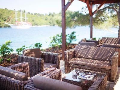 Przytulny zadaszony zestaw mebli z rattanu z widokiem na wodę i przystań jachtową.