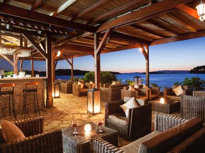 Otwarta restauracja na tarasie z meblami z rattanu, widokiem na morze i ciepłym oświetleniem