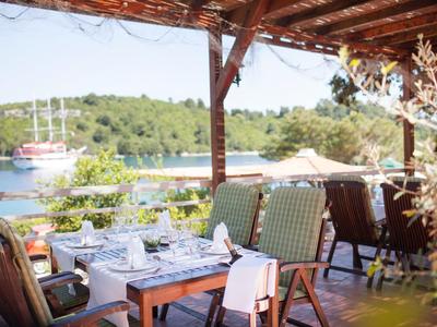 Zadaszony taras z jadalnią z widokiem na wodę i żaglówkę.