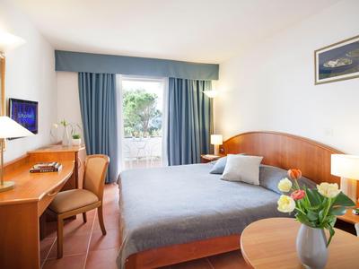 Przytulny pokój hotelowy z podwójnym łóżkiem, biurkiem i balkonem z widokiem na zewnątrz.