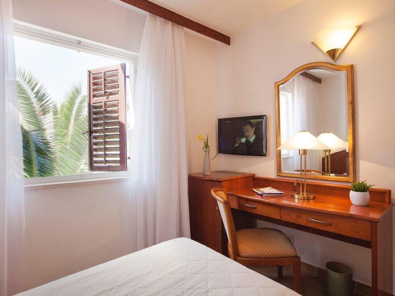 Jasna sypialnia z otwartym oknem, drewnianym biurkiem i lustrem