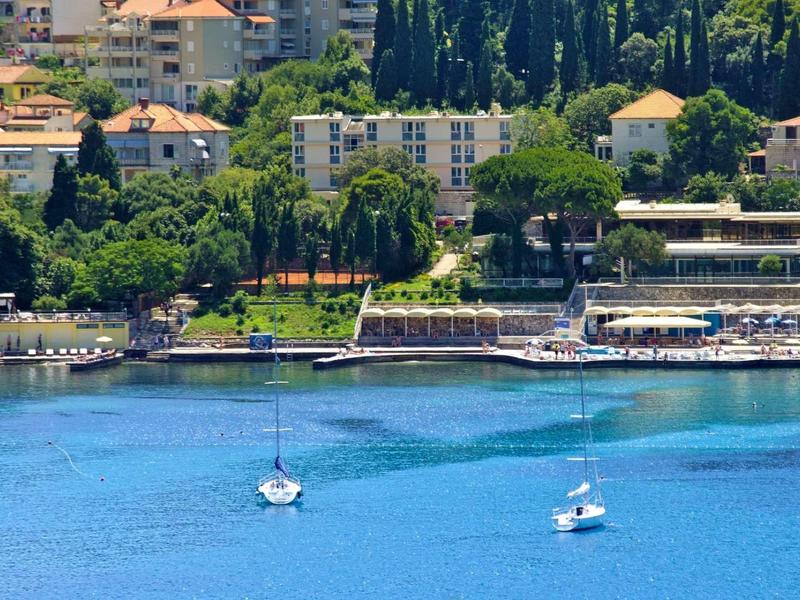 Uitzicht op een kustplaats met boten op helderblauw water en gebouwen op de achtergrond