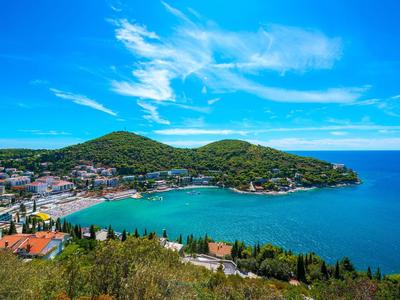 Vue d'une ville côtière avec des collines, la mer bleue et un ciel bleu éclatant.