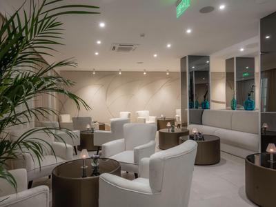 Nowoczesny hotelowy salon z wygodnymi białymi fotelami i okrągłymi stolikami.