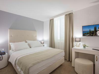 Brightly decorated hotel room with large bed, desk, and window with curtains.