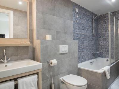 Modern bathroom area with toilet, sink, and bathtub designed in gray tones.
