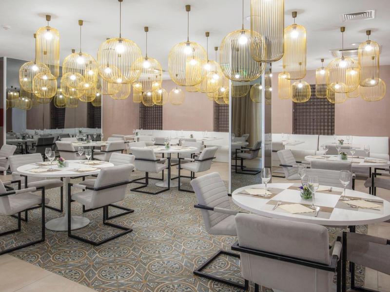 Modern restaurant area with white chairs and numerous hanging glass globe lights.