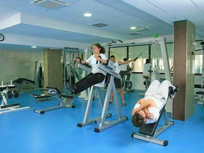 Due persone si allenano in una palestra moderna con attrezzi e pavimento blu.