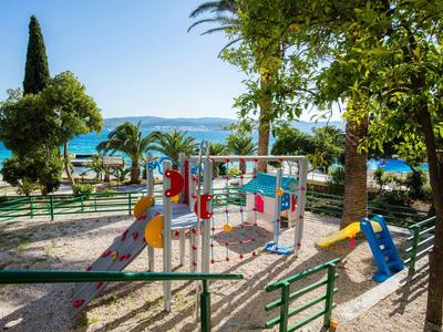 Speelplaats voor kinderen met glijbaan en klimrek bij het strand met zeezicht