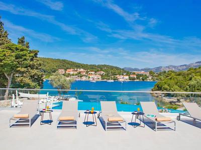 Sonnenterrasse mit Liegestühlen und Blick auf einen blauen Pool und eine grüne Landschaft.