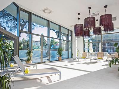 Heller Wellnessraum mit Liegestühlen und großen Fenstern mit Blick auf den See.