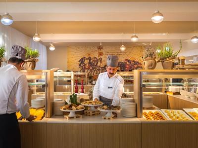 Buffet mit einer Vielfalt an Backwaren und einem Mitarbeiter, der einem Gast hilft.