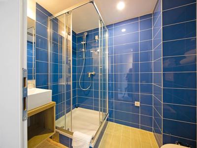 Moderner Duschbereich mit blauen Fliesen und Glasabtrennung in einem Badezimmer.