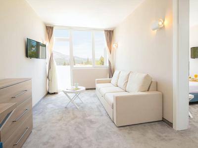 Modern eingerichtetes Hotelzimmer mit Sofa, Schreibtisch und Fenster mit Blick auf die Stadt.