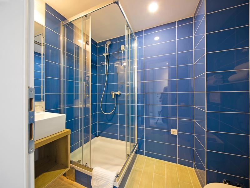 Moderner Duschbereich mit blauen Fliesen und Glasabtrennung in einem Badezimmer.