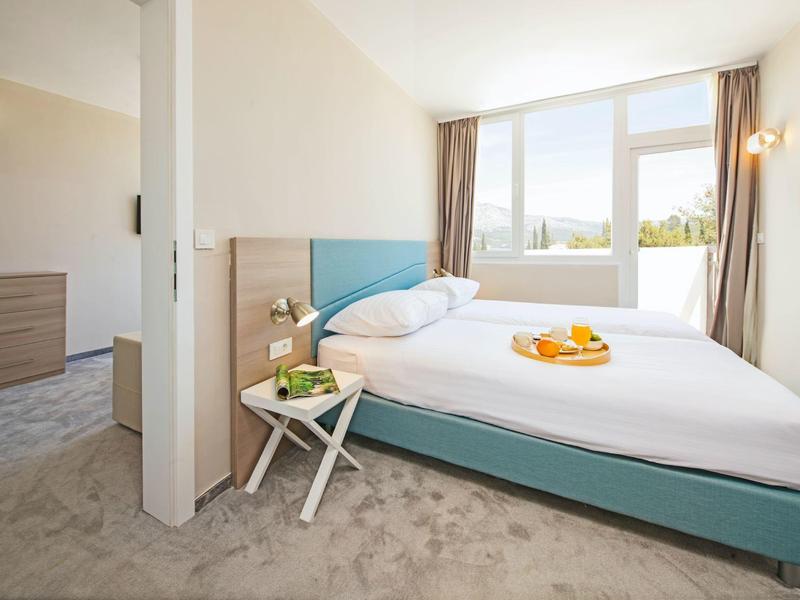 Helles Hotelzimmer mit großem Bett, Tageslicht und modernem Interieur.