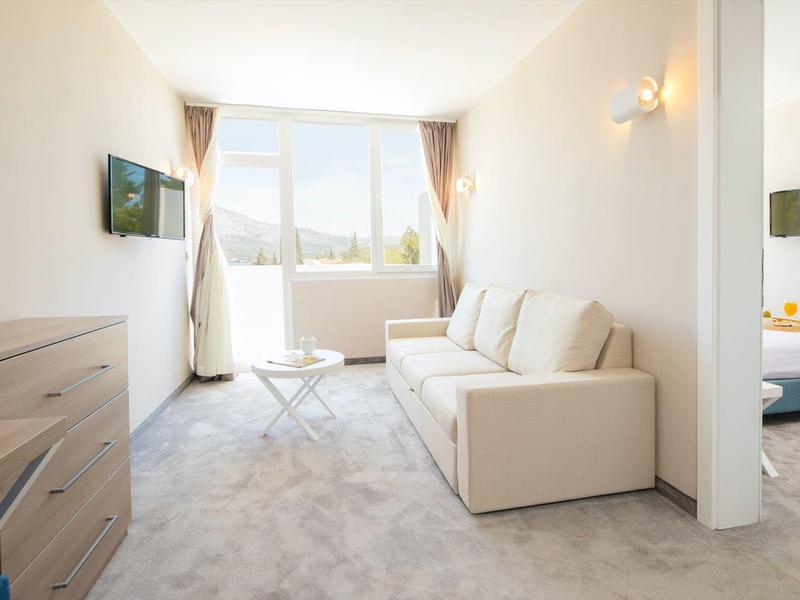 Modern eingerichtetes Hotelzimmer mit Sofa, Schreibtisch und Fenster mit Blick auf die Stadt.