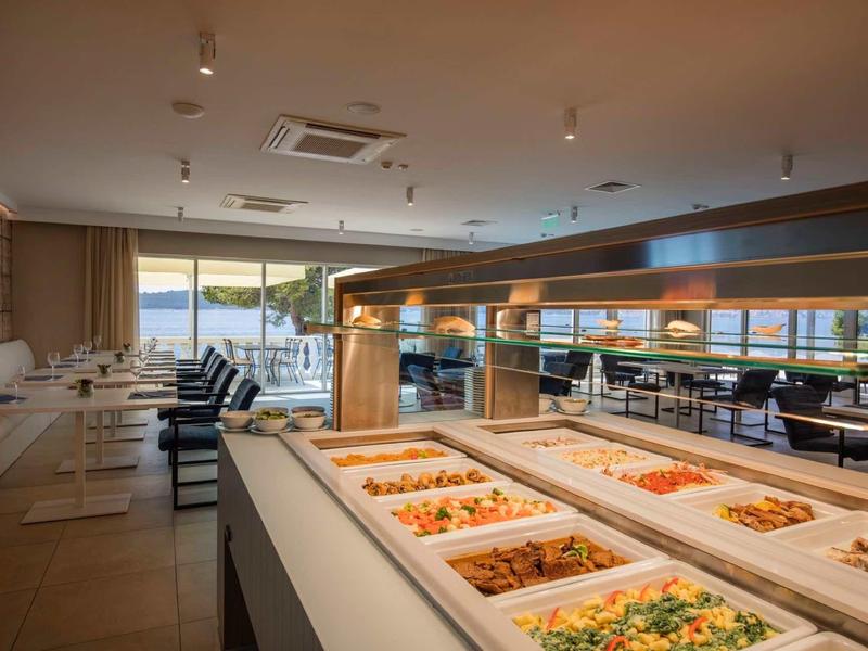 Elegant hotelrestaurant met buffet en uitzicht op zee door grote ramen.