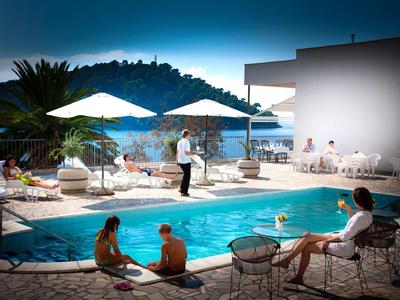 Hotel pool with guests relaxing, dining, and enjoying the sea view.