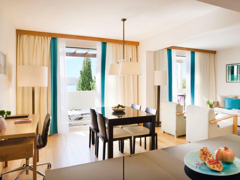 Světý moderní obývací pokoj s jídelním koutem, pracovním stolem a velkými skleněnými dveřmi na balkon.