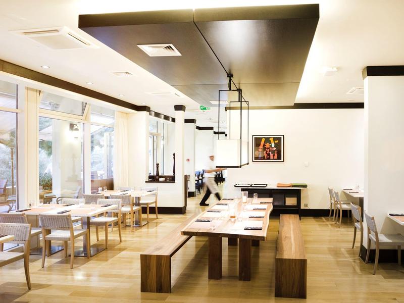 Světla, moderní restaurace s dřevěným a bílým nábytkem, velkými okny a funkčním osvětlením.