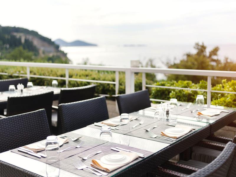 Elegantně prostřený stůl na terase s výhledem na pobřeží a moře.