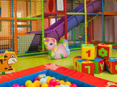 Colorful indoor play area with climbing frame, soft blocks, and ball pit in a hotel.