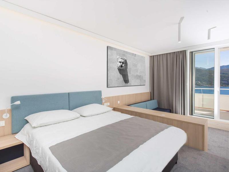 Modern hotel room with double bed, sea view, and terrace.