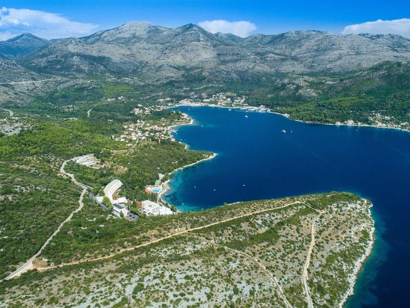 Aerial view of a coastal landscape with mountains, blue water, and small settlements.
