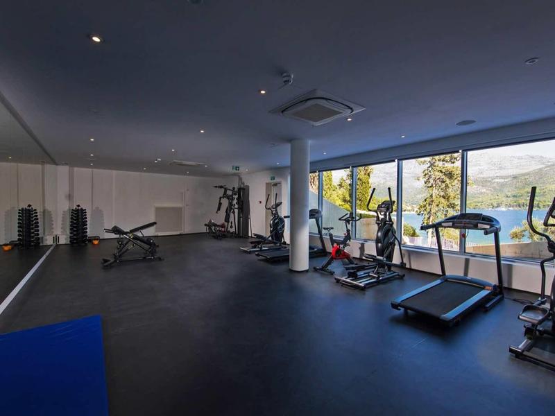 Bright gym with large windows, treadmills, and exercise machines overlooking a lake.