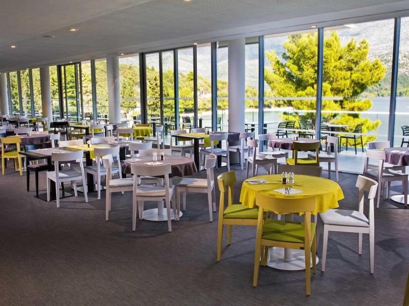 Bright restaurant with large windows overlooking water and mountains.