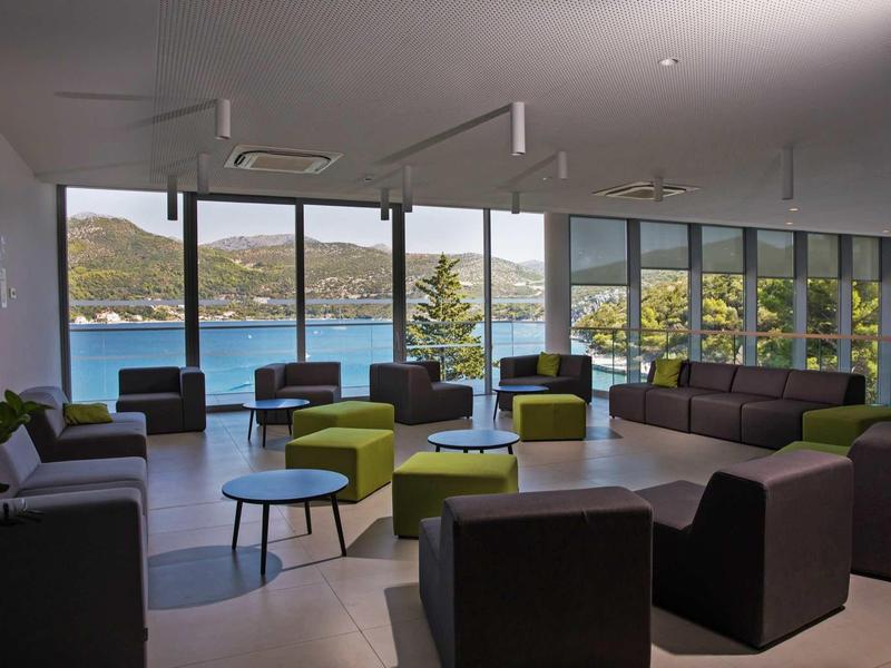 Modern lounge with large windows overlooking water and mountains.