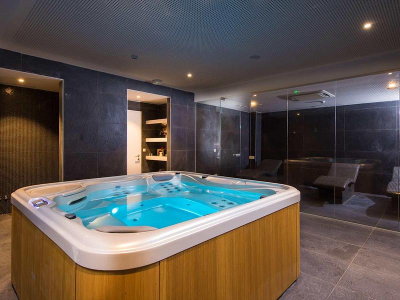 Modern hot tub in a stylish spa area with dark walls and dim lighting.