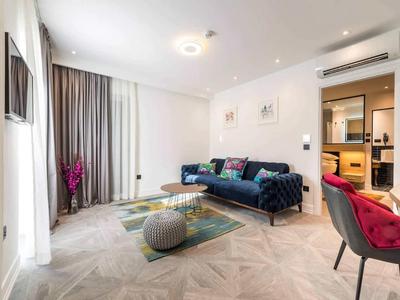 Modernes Wohnzimmer mit blauem Sofa, Teppich, roten Stühlen und großem Fenster mit Vorhängen.