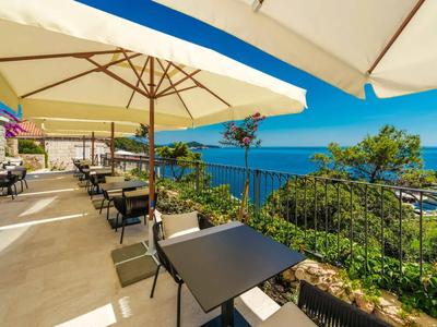 Balkon mit Tischen, Stühlen und Sonnenschirmen mit Meerblick.