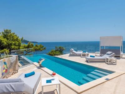 Moderner Poolbereich mit Liegen und Blick auf das Meer bei klarem Himmel.