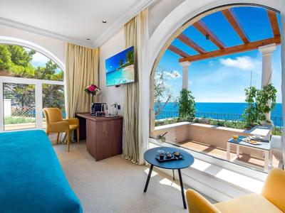 Camera d'hotel luminosa con terrazza e vista sul mare in una giornata di sole.