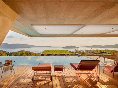 Moderner Balkon mit Infinity-Pool und Blick auf Seen und Hügel bei Sonnenuntergang.