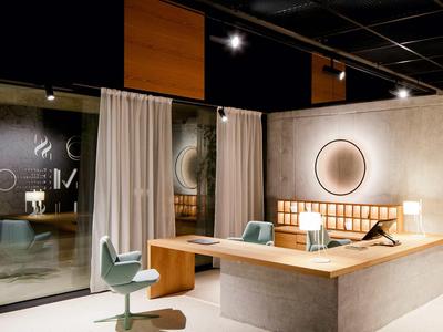 Moderner Hotel-Empfangsbereich mit Holztheke, rundem Spiegel und stilvollen Sitzgelegenheiten.