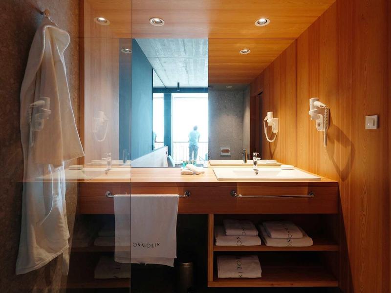 Modernes Badezimmer mit Holzwänden, Doppelwaschbecken, Handtüchern und einem großen Fenster.