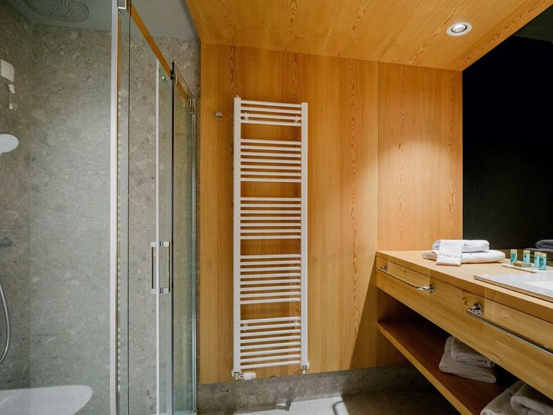 Modernes Badezimmer mit Holzverkleidung, Glasdusche, Handtuchheizung und Doppelwaschbecken.