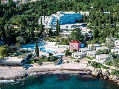 Complesso alberghiero con più edifici, piscine e accesso diretto al mare, circondato da vegetazione verde.
