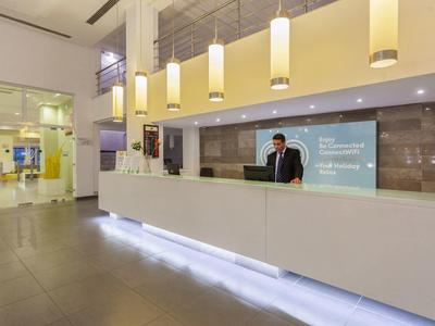 Comptoir d'accueil d'hôtel moderne avec éclairage et employé à la réception.