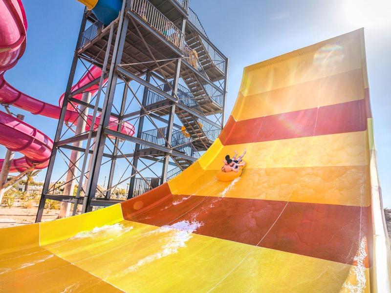 Toboggan aquatique avec plusieurs pistes et structure métallique sous un temps ensoleillé.