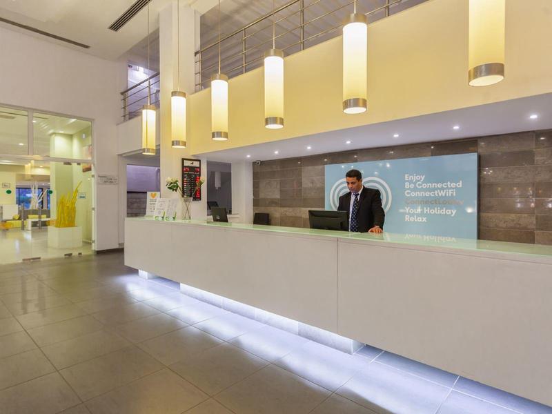 Comptoir d'accueil d'hôtel moderne avec éclairage et employé à la réception.