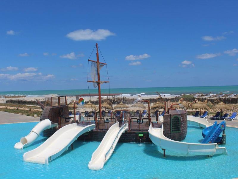 Aire de jeux aquatique pour enfants avec bateau et toboggans dans la piscine face à la mer