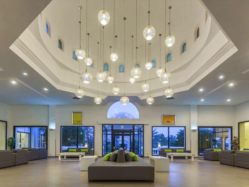 Grand hall d'hôtel avec éclairage moderne et sièges élégants sous un plafond haut.