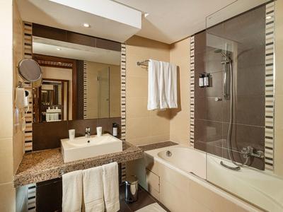 Modernes Badezimmer mit Badewanne, Waschbecken und großen Spiegeln in neutralen Farbtönen.