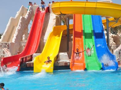 Bunte Wasserrutschen führen in ein Schwimmbecken mit Kindern beim Rutschen und Spaß.